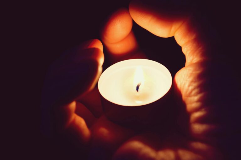 A pair of hands cradling a candle creating a soft and warm illumination.