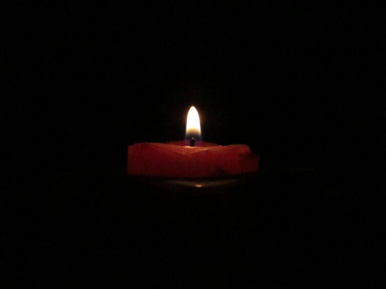 red lighted candle on dark room