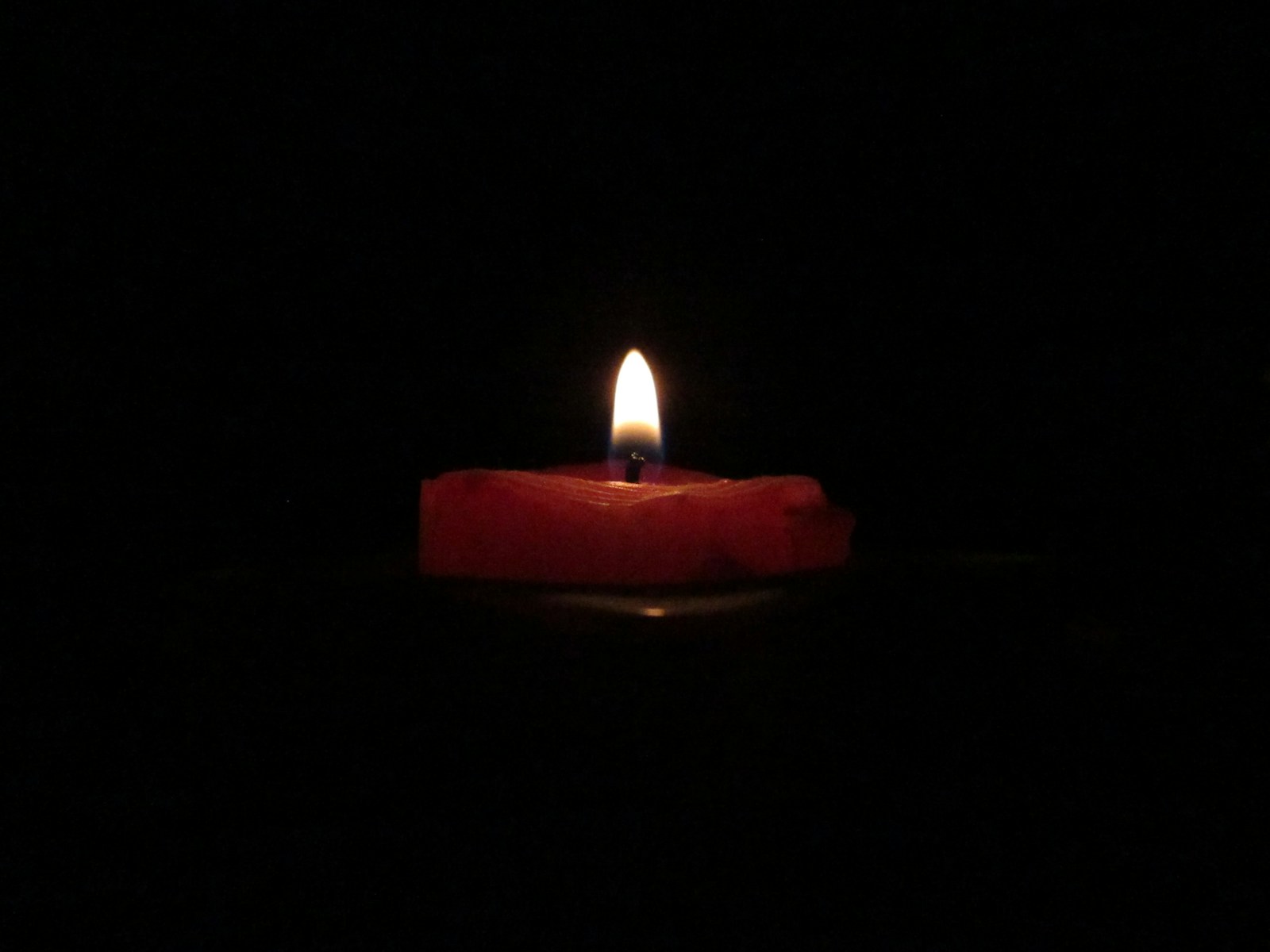 red lighted candle on dark room